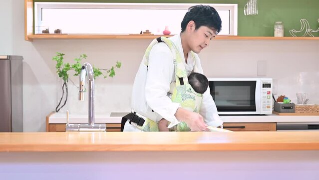 Video of a father putting his baby to sleep while washing dishes in a one-person operation.
