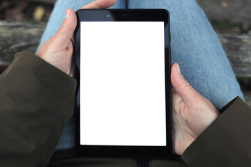 woman holds a tablet in her hands with a white, blank screen for design, copy space