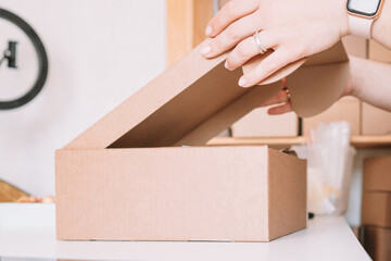 Cropped photo of woman hands packing, preparing parcel for delivery package to customers. Small business, online order