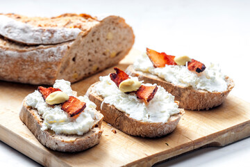 garlic spread on slice of bread served with bacon, grated cheese and mustard