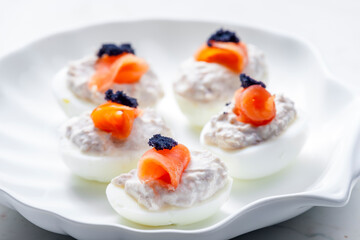 boiled eggs filled with tuna fish spread and smoked salmon and  black caviar on the top