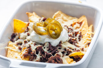 nachos with beef minced meat and cheese served with whipped cream and jalapenos