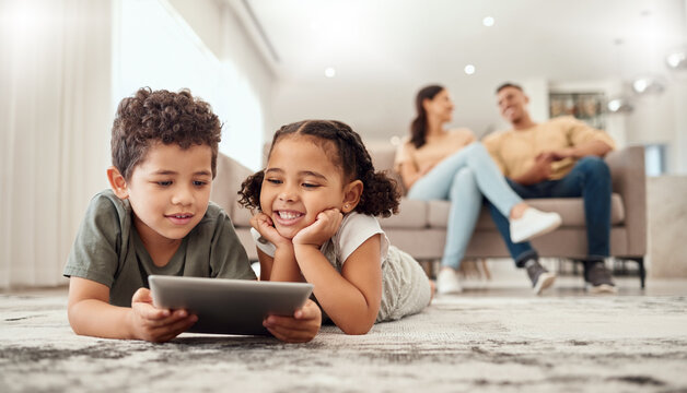 Learning, tablet and children streaming a video on technology on the living room floor of their house. Education, happiness and movies on technology for kids with parents on the sofa in their home