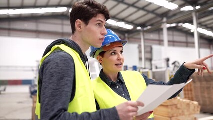 workers of a carpentry shop talking, mature female boss discusses showing plans, with young store clerk.