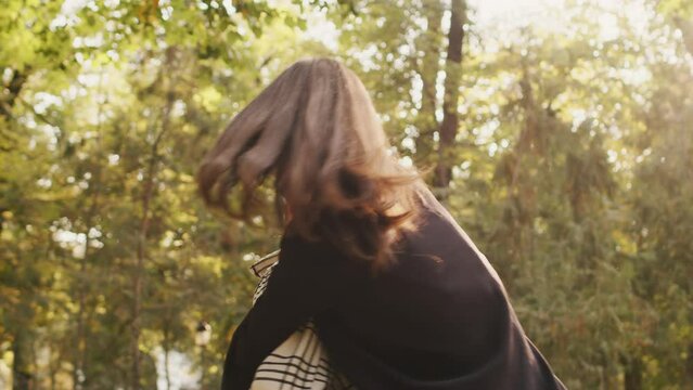 Joyful young man giving piggyback ride to happy beautiful woman, spinning around, talking, laughing outdoors