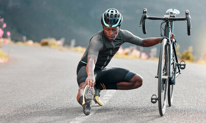 Outdoor, cycling and cyclist doing stretching exercise by his bicycle on road in mountain. Sports,...