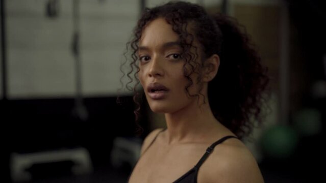 Young biracial woman wearing boxing gloves breathing and boxing at the gym