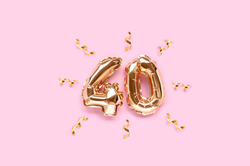 Number fourty golden foil balloons with ribbon confetti on a pink pastel background.