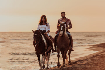 A loving couple in summer clothes riding a horse on a sandy beach at sunset. Sea and sunset in the...