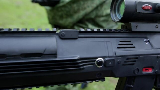a weapon with a digital display in the hands of a military man with a forest. High quality FullHD footage
