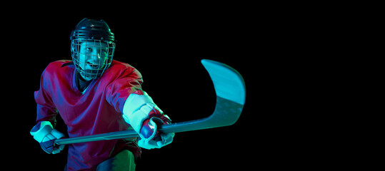 Powerful throw. Male ice hockey player in sports protective uniform in action over dark background...