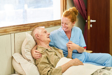 Altenpflegerin am Bett von Senior beim Hände halten
