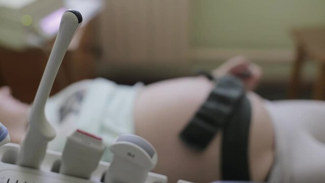 Ultrasound diagnostic sensors against the background of the belly of a pregnant woman who does cardiotocography. The concept of fetal ultrasound during pregnancy, medical examination.