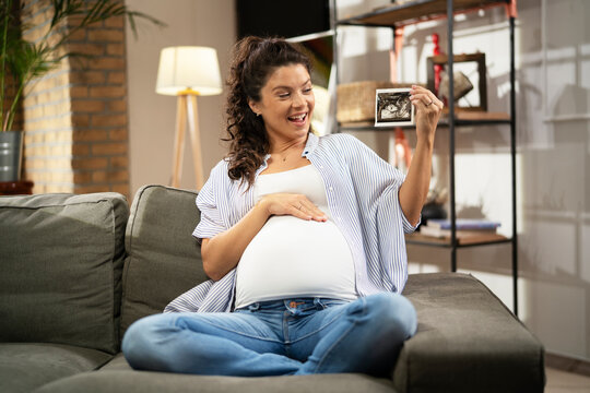 Pregnant woman with ultrasound photo. Beautiful pregnant woman enjoy at home..