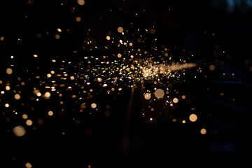 Sparks in dark. Stream of lights on black background. Metal crushing. High temperature.