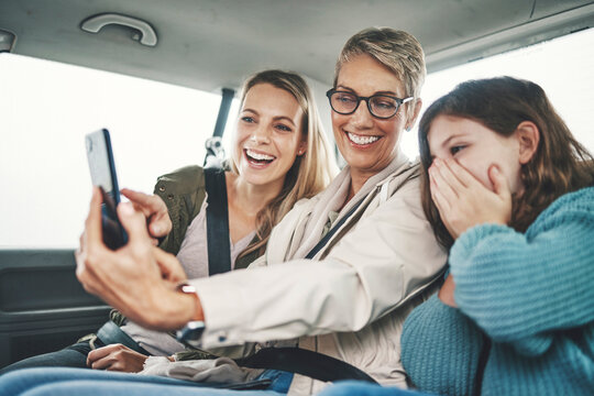 Family, phone and women taking a selfie in the car on road trip adventure. Grandmother, mom and girl smile for picture on smartphone in backseat for memories of holiday, journey and vacation weekend