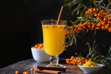 Tea of sea-buckthorn berries with branch on dark wooden background