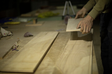 Carpenter holds tree. Worker chooses board. Details of carpentry workshop.