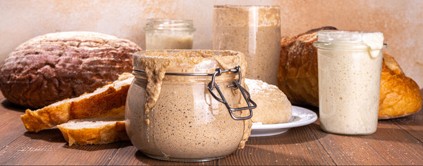 Healthy lifestyle, gluten free fermenting diet. Homemade sourdough. Active bubbly rye, wheat, oat sourdough with different flour and fermentation methods, in glass jars, with raw dough and baked bread