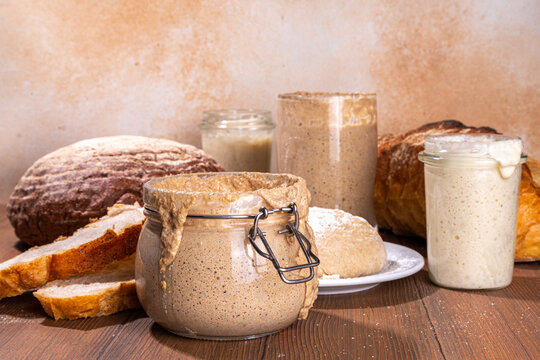 Healthy lifestyle, gluten free fermenting diet. Homemade sourdough. Active bubbly rye, wheat, oat sourdough with different flour and fermentation methods, in glass jars, with raw dough and baked bread