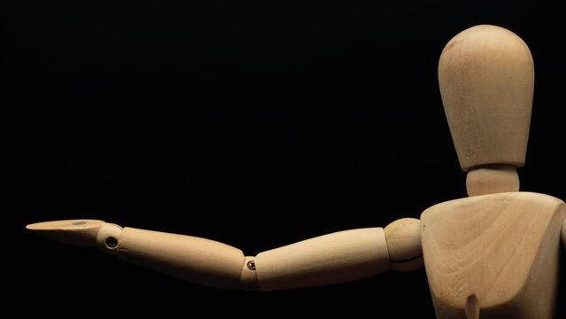 wood mannequin raises right hand.