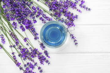 Cup with lavender tea and lavender flowers on wooden backgorund.