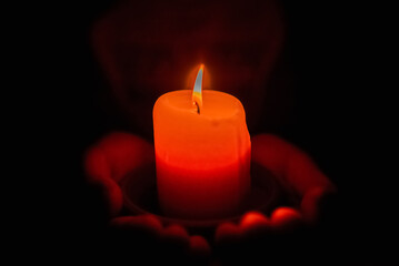 Little boy holding red burning candle in the darkness.Selective focus.Closeup.