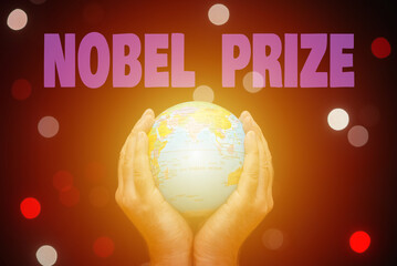 The inscription NOBEL PRIZE.A Man's hands hold a world globe in a darkness glowing small bubbles...