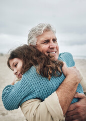 Happy, beach and grandfather hug a girl at the sea together on holiday. Happiness, love and elderly man in retirement smile, embracing and bonding with his toddler grandchild or kid on vacation - obrazy, fototapety, plakaty