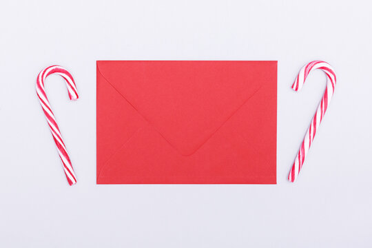 Red envelope and red candy canes on a grey background. Christmas and New Year concept. Mockup, copy space.