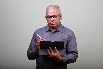 Portrait of a senior man of Indian ethnicity looking at tablet computer