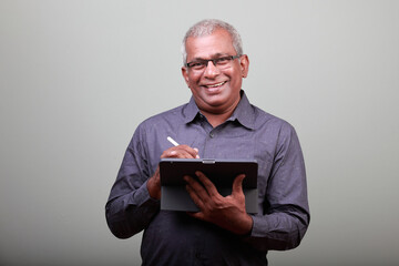Portrait of a smiling man of Indian ethnicity holding a tablet computer