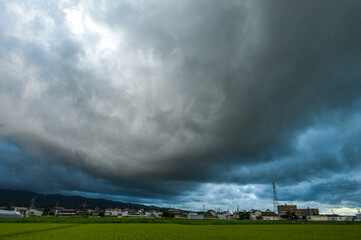嵐の前の暗雲が広がる農村の風景
