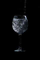 water pouring into glass on black background