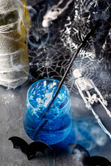 Blue cocktail for halloween party in glass with bubbling and smoke.