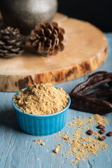 Carob pods and carob powder over a blue wooden background.