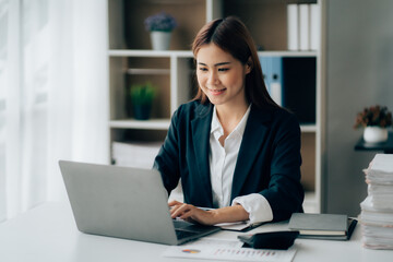 Asian Business woman using calculator and laptop for doing math finance on an office desk, tax, report, accounting, statistics, and analytical research concept