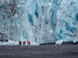 Tourists standing in front of the Aialik Glacier, coming off the Harding Ice Field, Kenai Fjords National Park