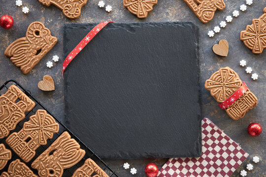 Speculoos or Spekulatius, Christmas biscuits, chocolate balls and stripy towel on dark textured background. Traditional German sweets, cookies for Xmas, Advent. Copy-space on black slate stone plate.