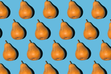 Colorful pear pattern. Yellow and orange Bera pears on a blue background. Ripe juicy fruits top view. Food background. Creative concept.