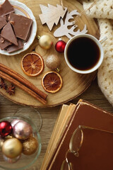 Cup of tea or coffee, various sweets and spices, Christmas decorations, comfy blanket, books and glasses. Top view.