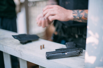 Firearms in professional hands. Men's hands, bullets and a gun.