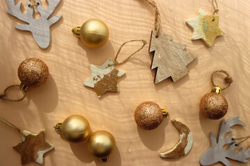 Christmas tree ornaments in neutral and gold colors, illuminated by sunlight. Flat lay.