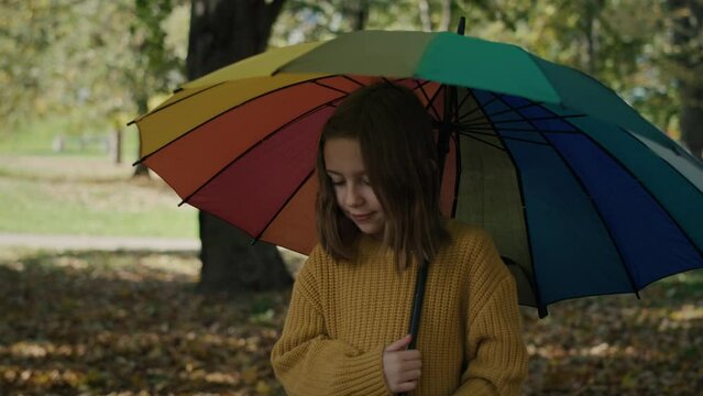 Caucasian girl walking across the park with colorful umbrella. Shot with RED helium camera in 8K.  