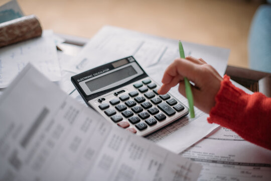 The hands of an elderly woman with a calculator and a lot of utility bills. Pensioner and payment of utilities for heating
