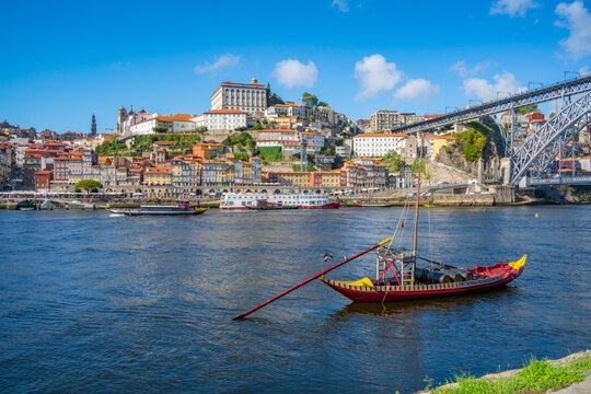 View of the Dom Luis I bridge over Douro River and Rabelo boat aligned with colourful buildings, UNESCO World Heritage Site, Porto, Norte