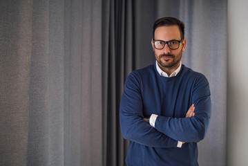 Portrait of confident handsome man, posing in front of the gray background.