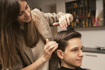 Hair salon master does hair styling client at barber shop. Men's fashion and style. Hair care,...