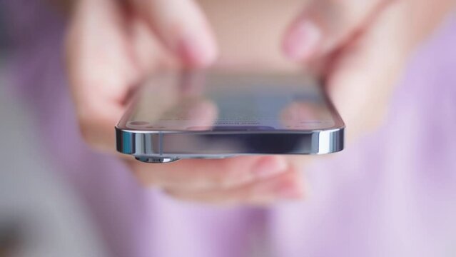 A close-up of the hands of a person with pink nails writes a text message in the manager against a delicate pink background. Quick correspondence in a social network on a new modern phone.