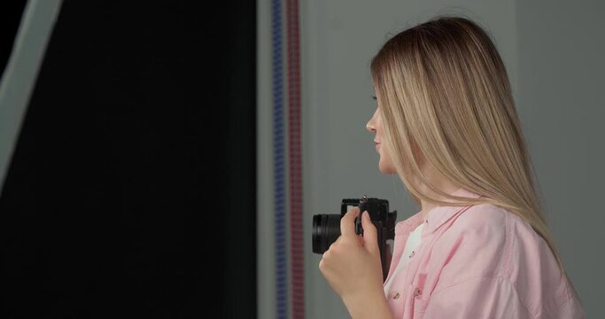 Young beautiful professional photographer taking picture with modern camera  indoors